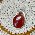 Colgante artesanal de plata de ley 925 con cornalina naranja rojiza en cabujón ovalado y símbolo Semilla de la Vida soldado en relieve por detrás